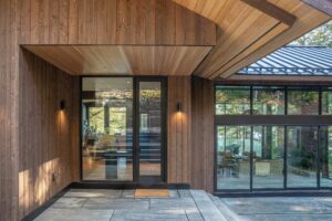 Natural light filtering through large glass entryway of a custom Alderstone Homes build in Ontario, highlighting warm wood cladding and modern architectural design.