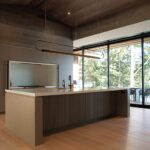 Modern kitchen interior at Muskoka Cottage by Alderstone Homes, featuring minimalist cabinetry, custom lighting, and expansive forest views.